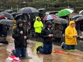 100 Austrālijas vīri lielā lietū lūdzas Rožukroni
